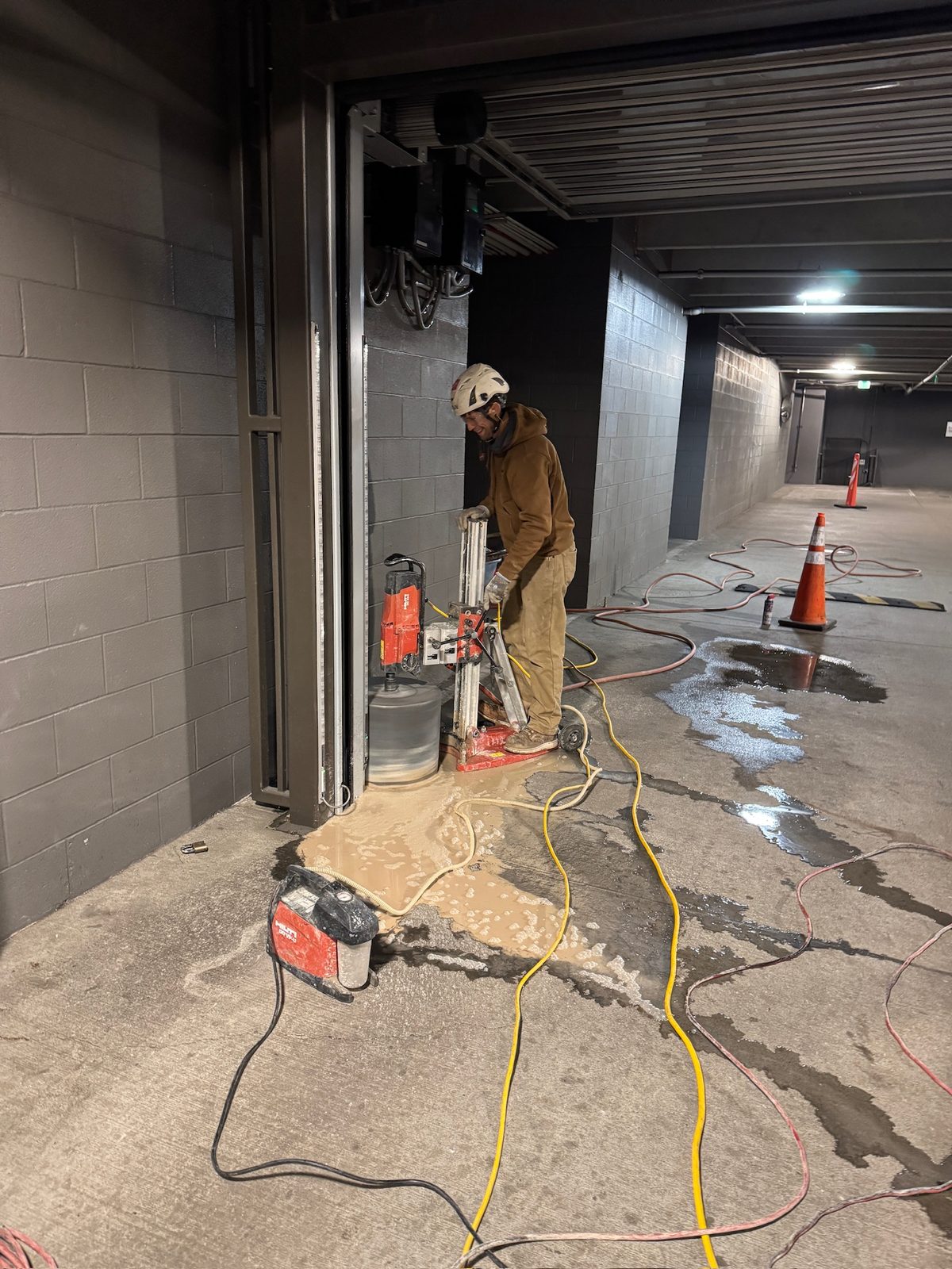 Rig-mounted core drill boring an 18-inch core at a parking garage door opening for a bollard installation