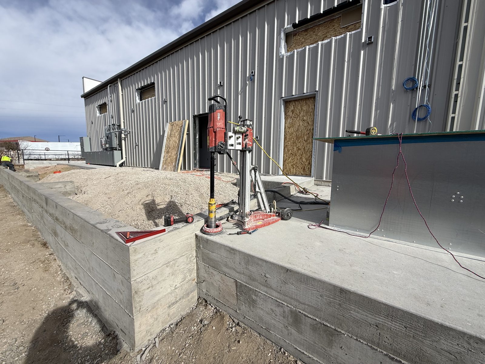 Small-diameter core rig on a vacuum pad with automatic slurry collection, drilling a deep drainage-line core on a finished site
