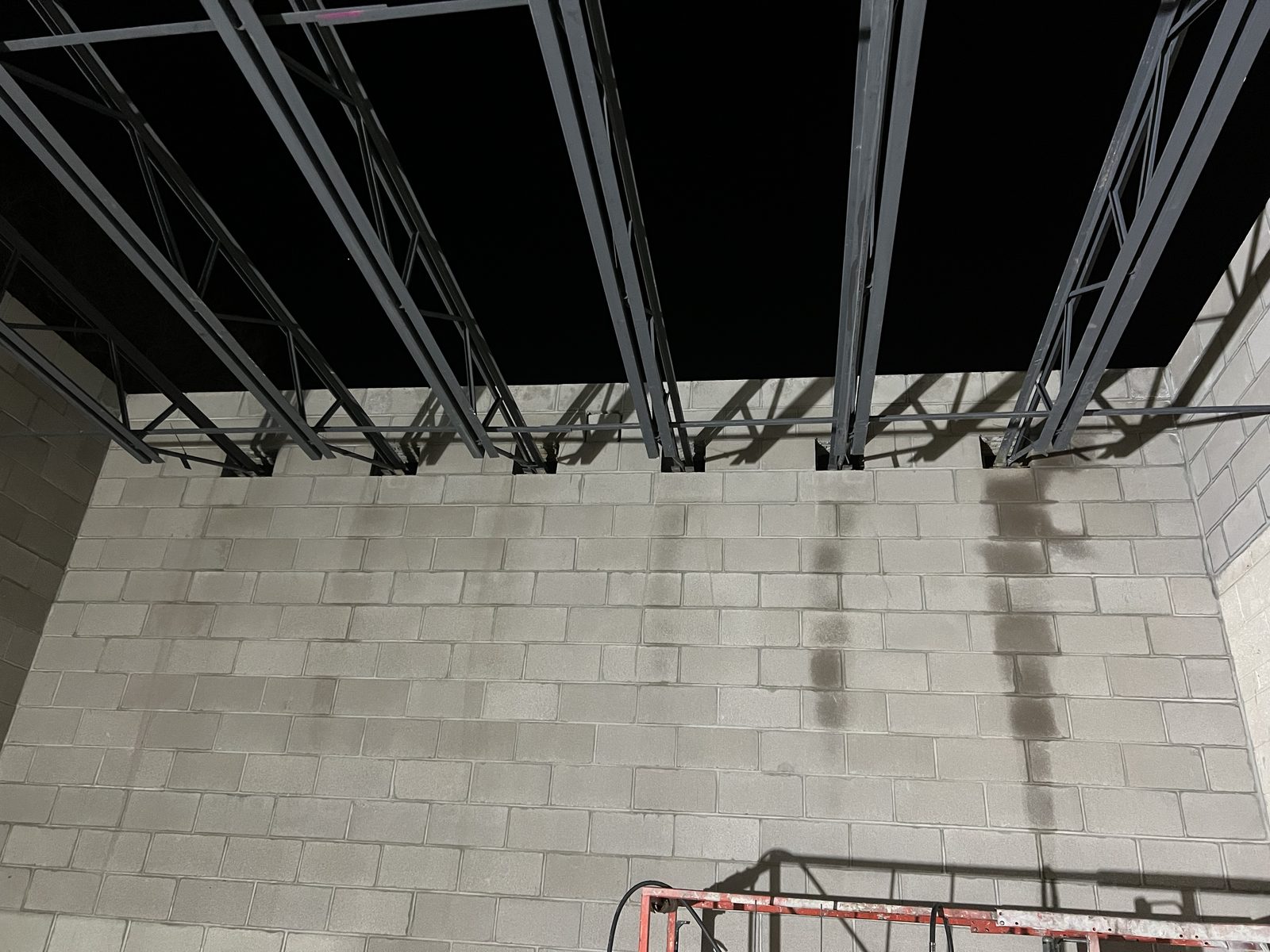 Operator hand sawing between rebar dowels on a stem wall during a joist installation on a tight commercial timeline