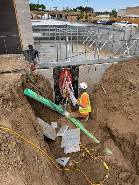 Drainage line being guided into an 8-inch core drilled from a vacuum-pad-mounted rig