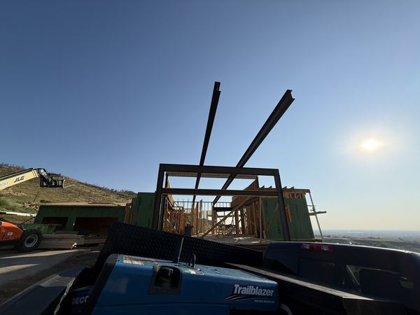 Crane setting structural steel beams into position on a custom residential build