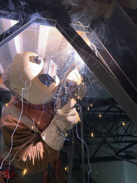 Welder in full leathers making overhead welds on RTU reinforcement angles